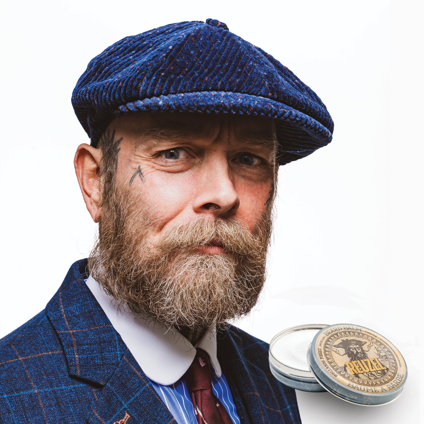 Male model with white and blonde beard next to open container of REUZEL beard balm