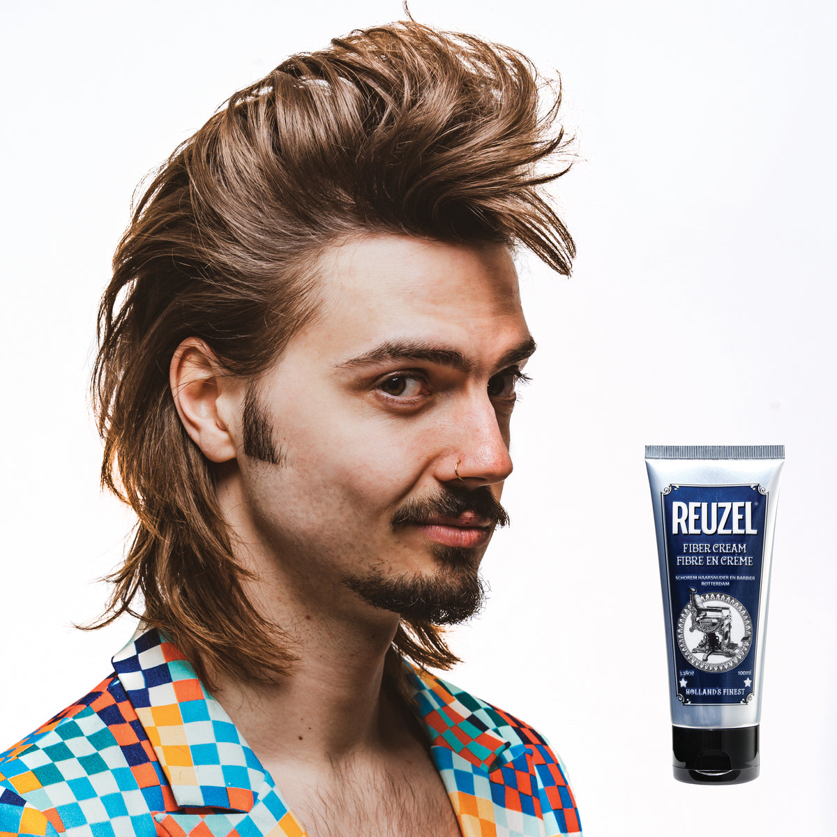 Male model with brown straight mullet next to tube of REUZEL fiber cream