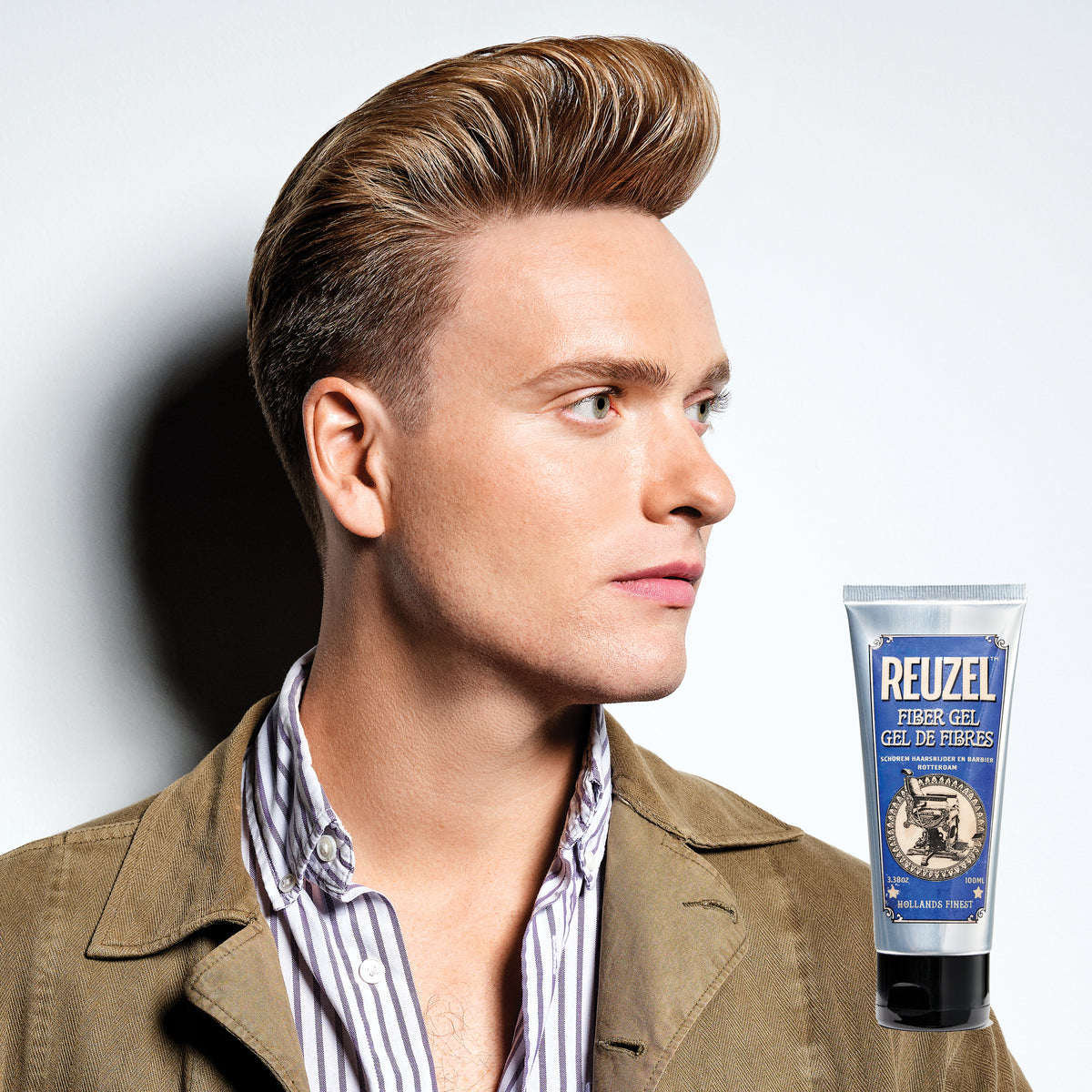 Male model with brown short hair next to REUZEL fiber gel