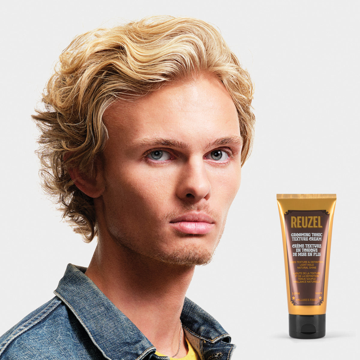 Male model with blond wavy hair and beard next to REUZEL Grooming Tonic Texture Cream