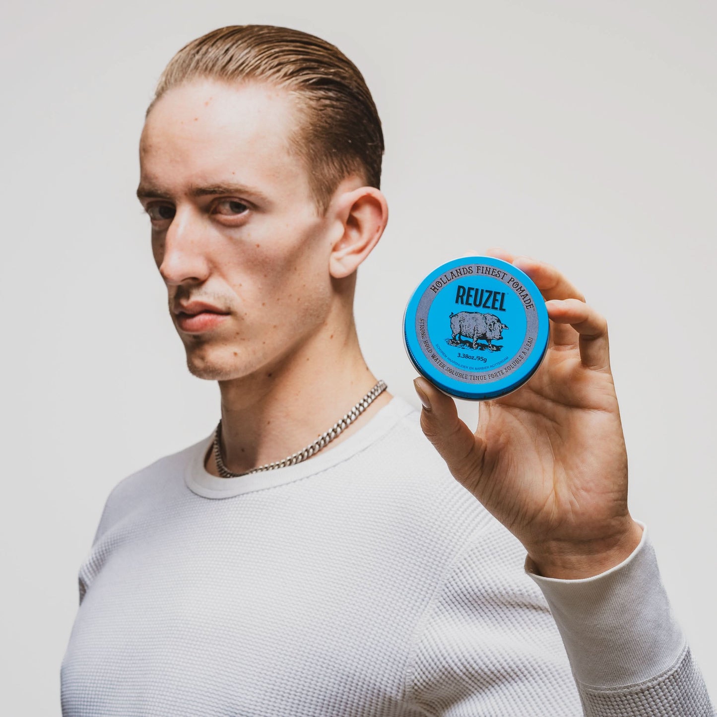Clean shaven model with slick backed hair styled with Blue High Shine Strong Hold Pomade