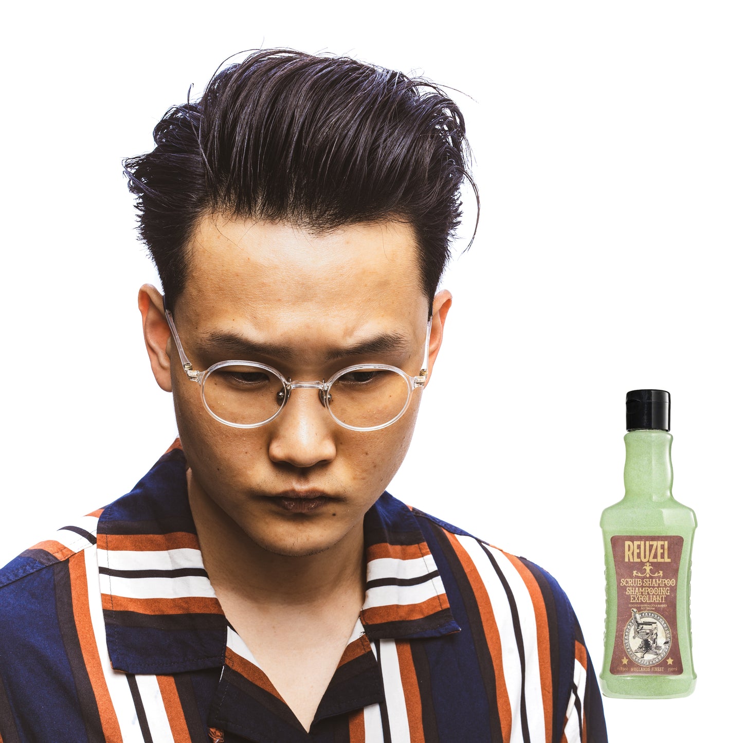 Male model with black hair next to REUZEL scrub shampoo