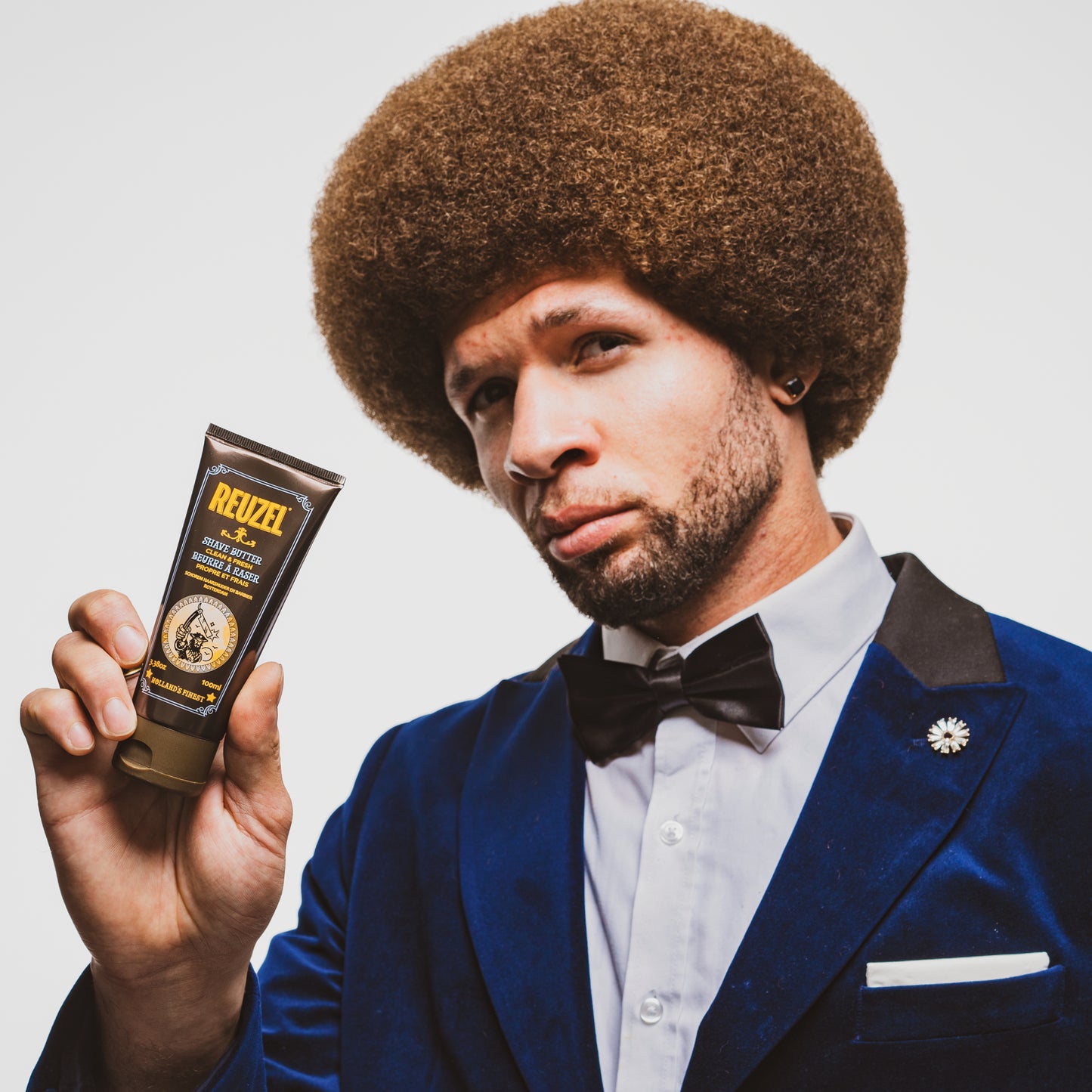 Male model with brown afro holding REUZEL shave butter