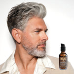 Male model with grey hair and beard next to REUZEL Beard Oil
