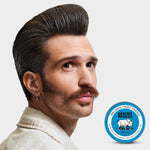 Man with slicked-back hairstyle and mustache styled using a strong-hold, high-shine REUZEL pomade