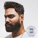 Man with a short, textured haircut and matte finish styled with clay pomade, shown alongside a tin of REUZEL Clay Matte Pomade as an example of a natural, no-shine hairstyle.