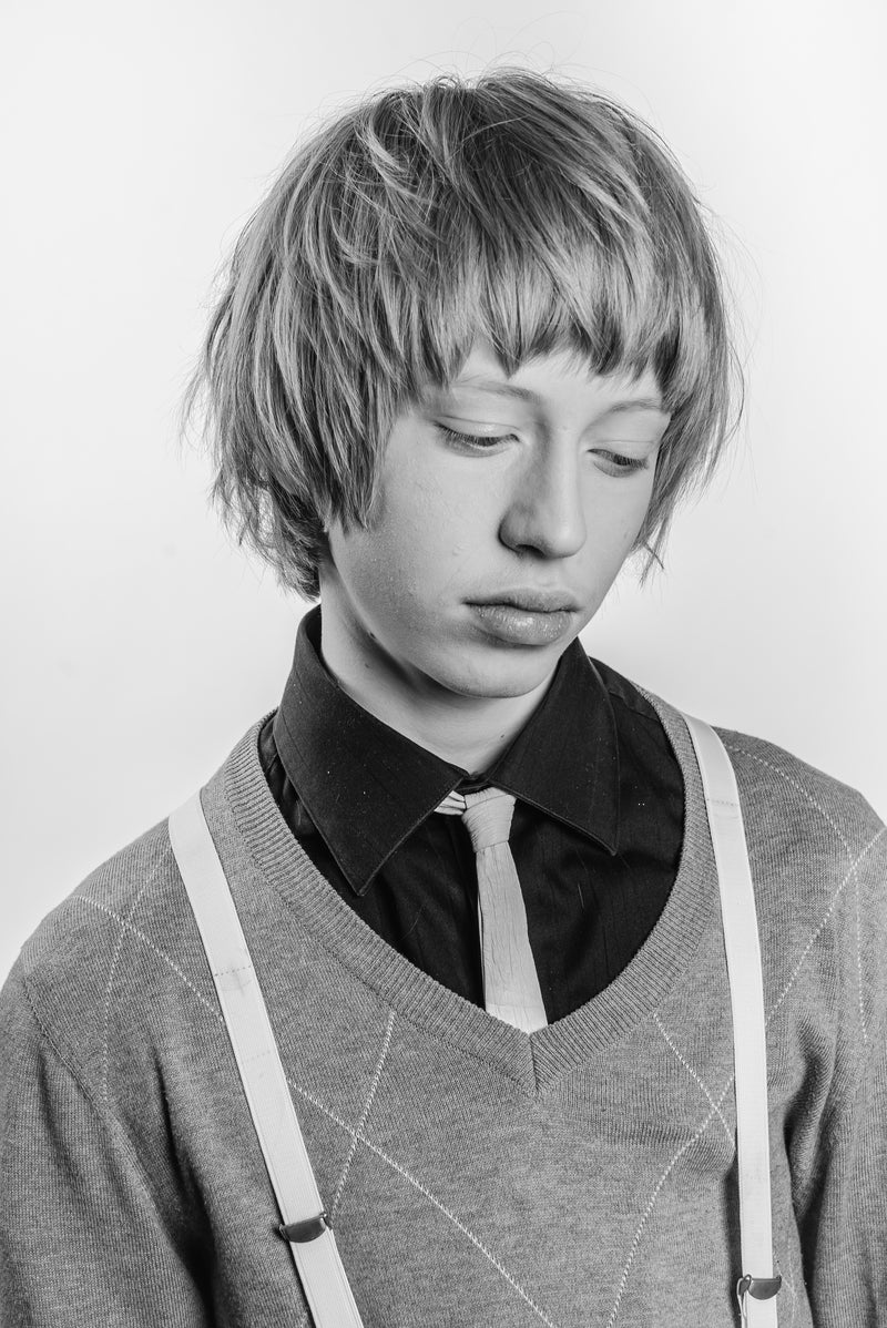 Textured haircut on young man wearing a tie and suspenders.
