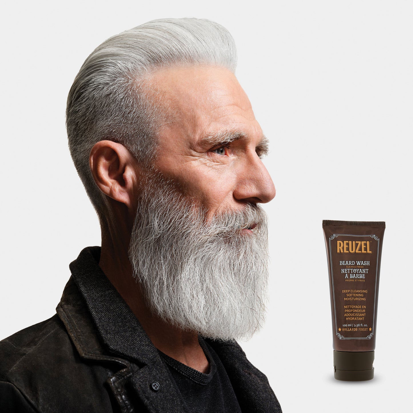 Male model with short white hair and medium beard next to REUZEL beard wash