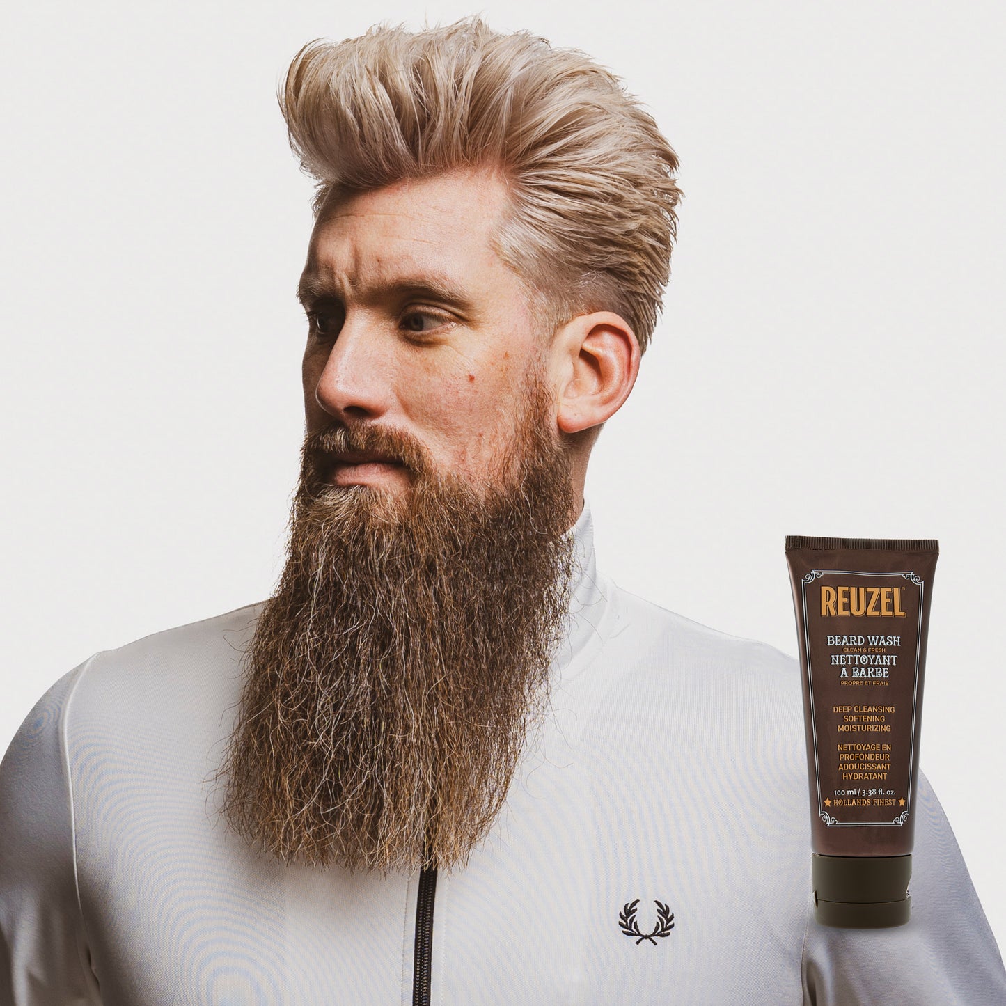 Male model with blonde hair and long full beard next to REUZEL beard wash