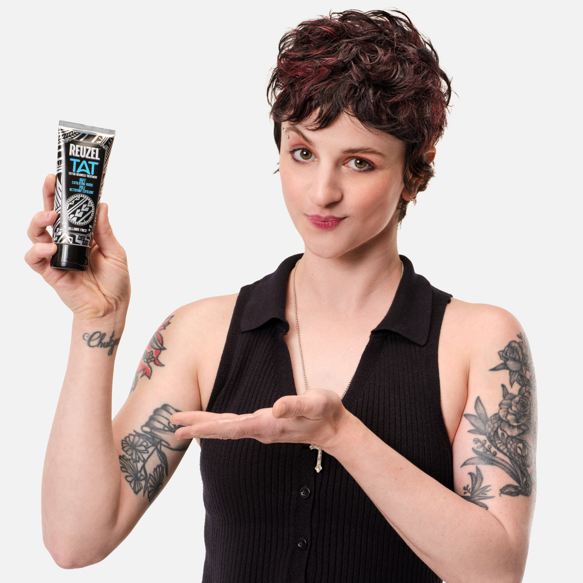 REUZEL Buff exfoliating tattoo scrub. Image of female model with short brown hair holding BUFF exfoliating wash.