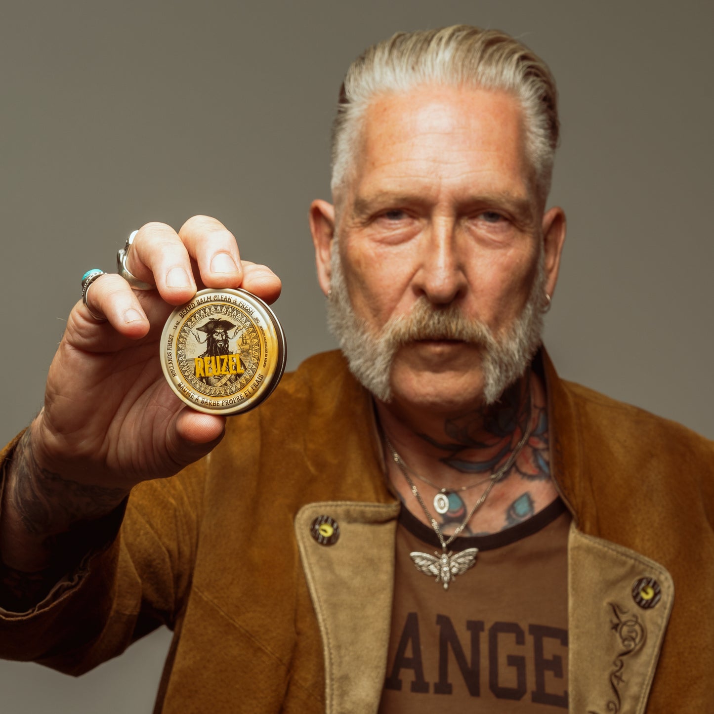 Man with grey hair and beard styled with REUZEL beard balm 