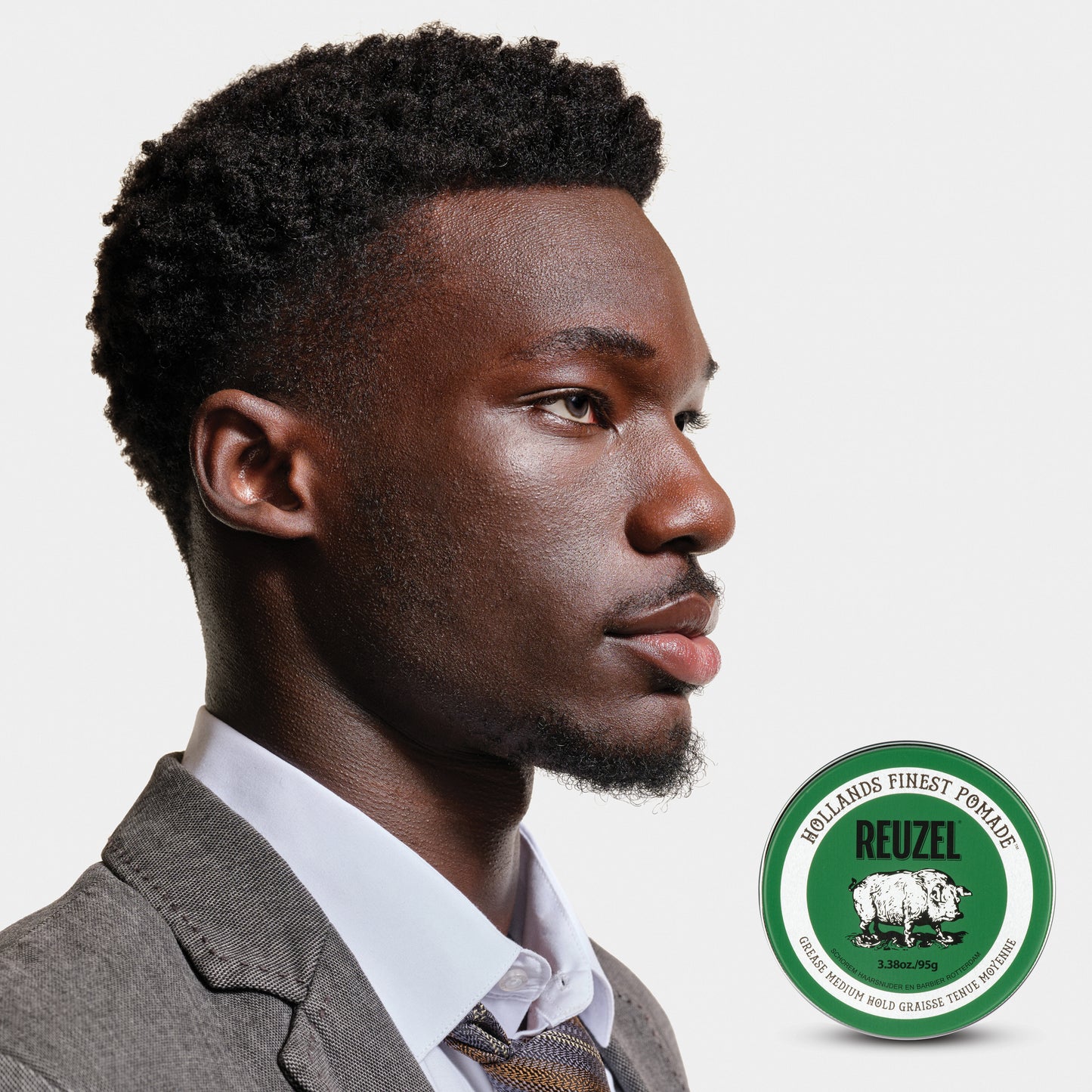 Man with brown textured curly hair styled with REUZEL grease medium hold pomade.