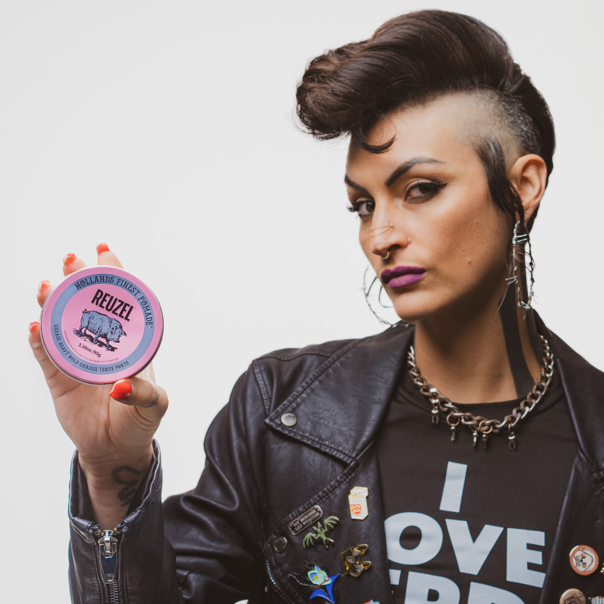 Female model with short hair holding REUZEL pink pomade grease heavy hold